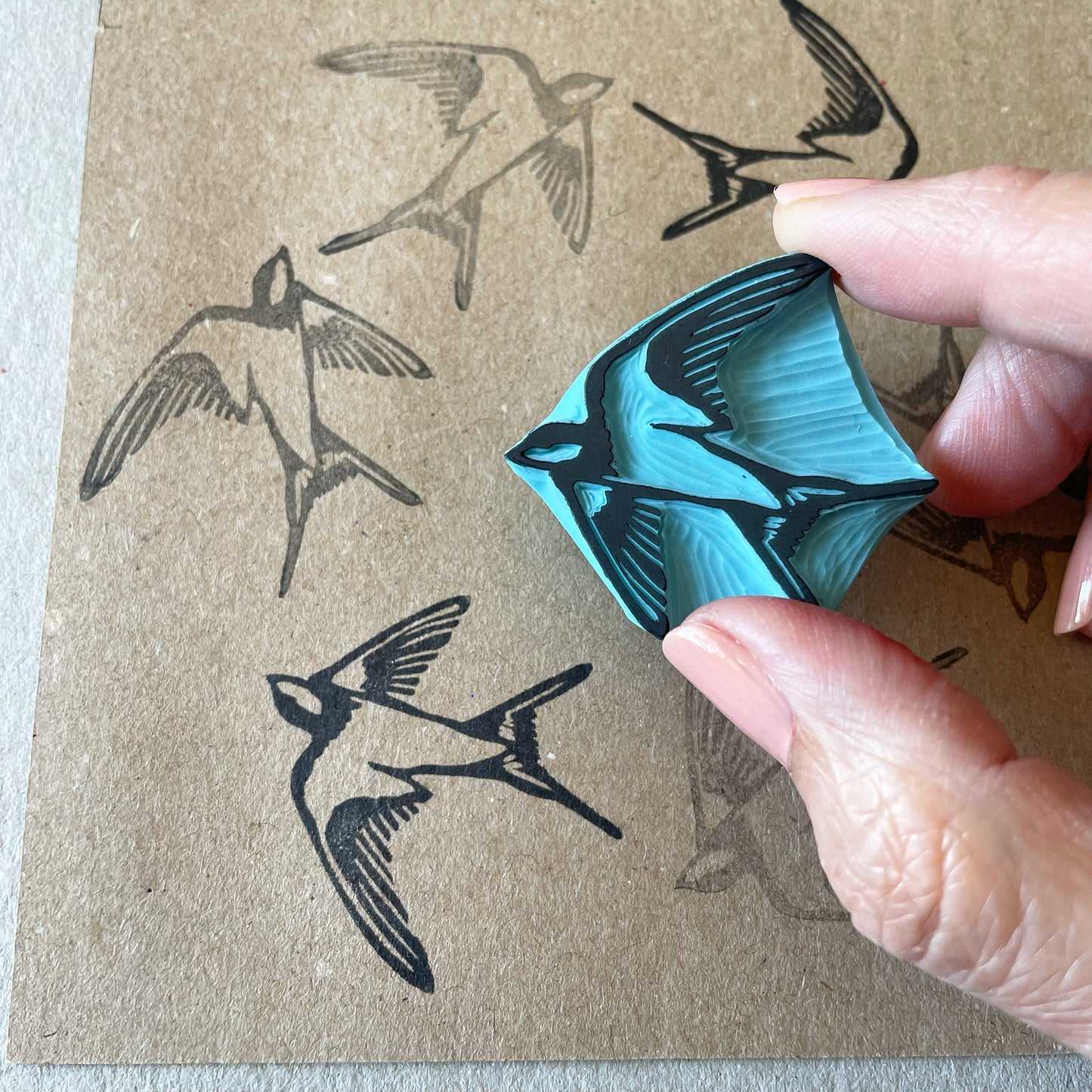 hand holding a hand carved rubber stamp of a swallow bird