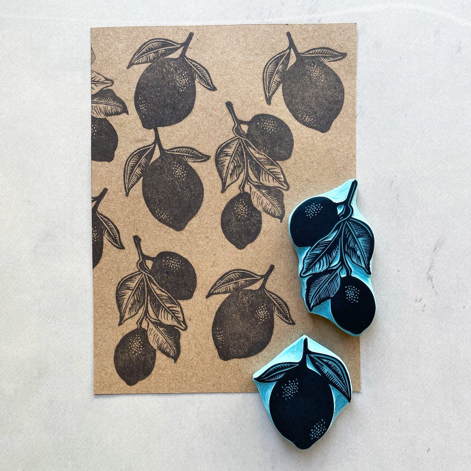 Hand carved lemon rubber stamps with leaf detail beside stamped kraft paper pattern
