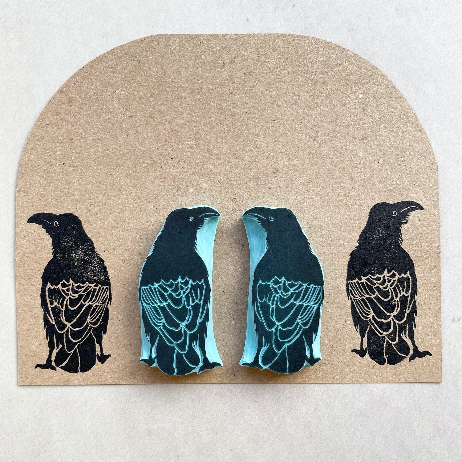 Hand carved raven rubber stamps and matching ink prints on textured brown paper