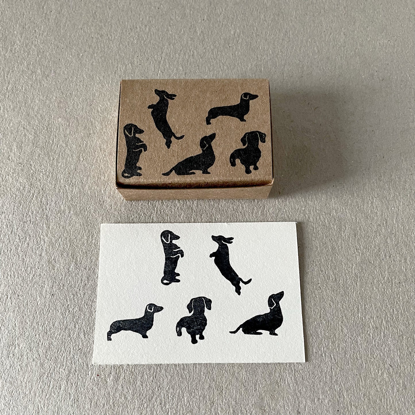 Small dachshund silhouette rubber stamps arranged next to printed dog impressions.