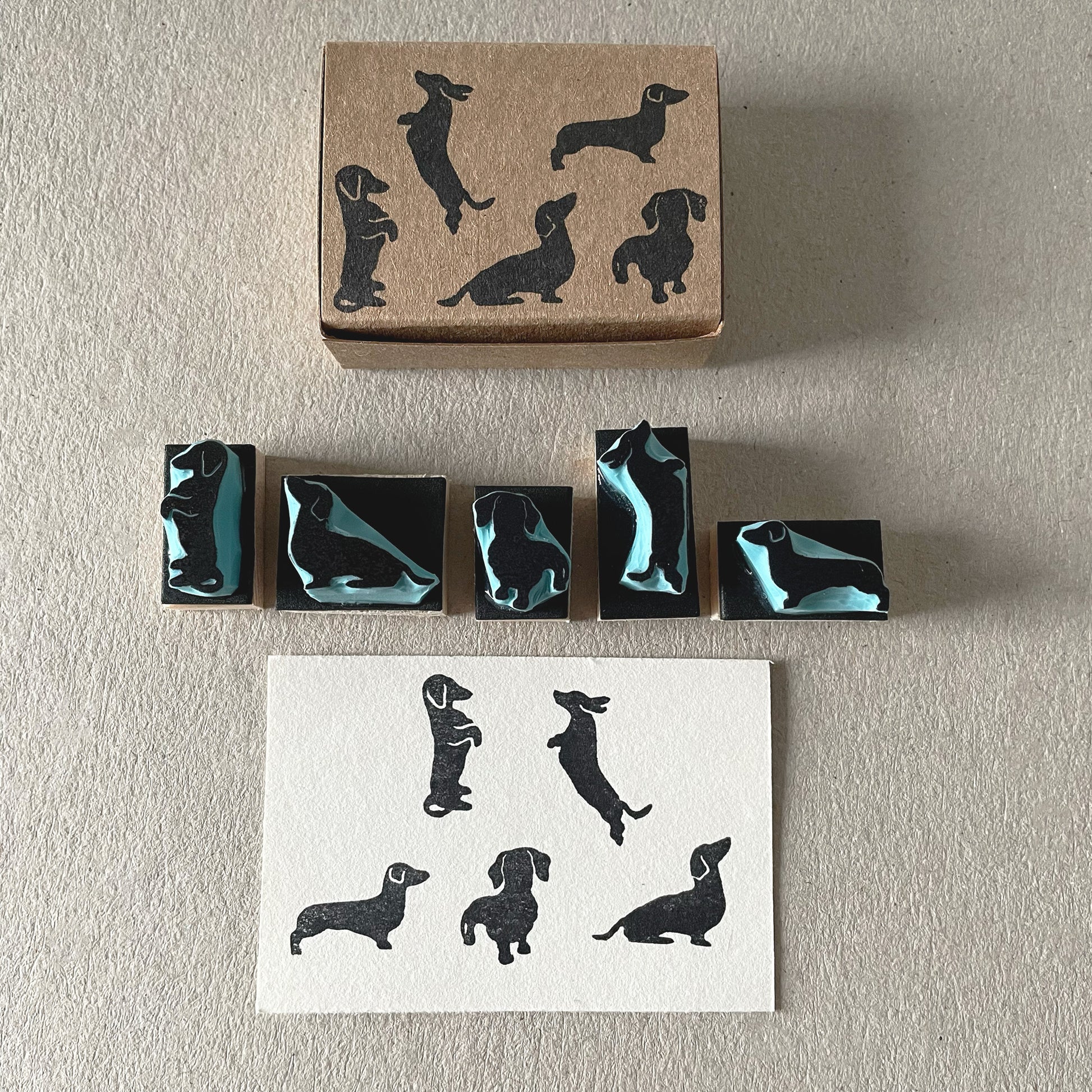 Small dachshund silhouette rubber stamps arranged next to printed dog impressions.